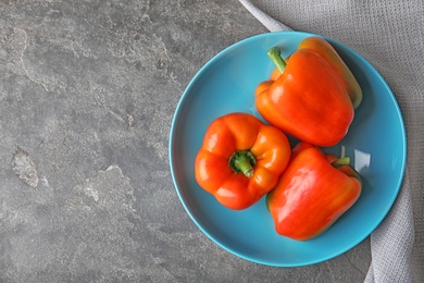 Plate with ripe paprika peppers on grey background, top view