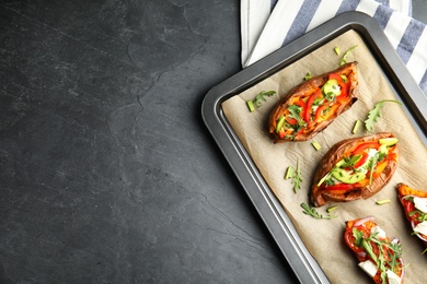 Baking sheet with stuffed sweet potatoes on grey background, top view. Space for text