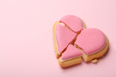 Photo of Broken heart shaped cookie on pink background, space for text. Relationship problems concept