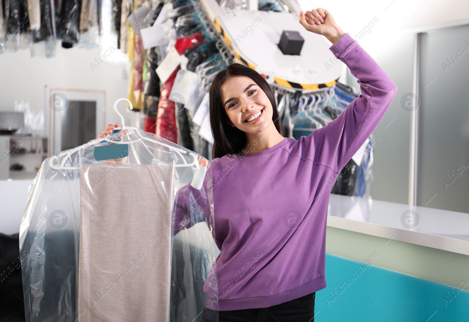 Photo of Happy client with clothes near counter at dry-cleaner's