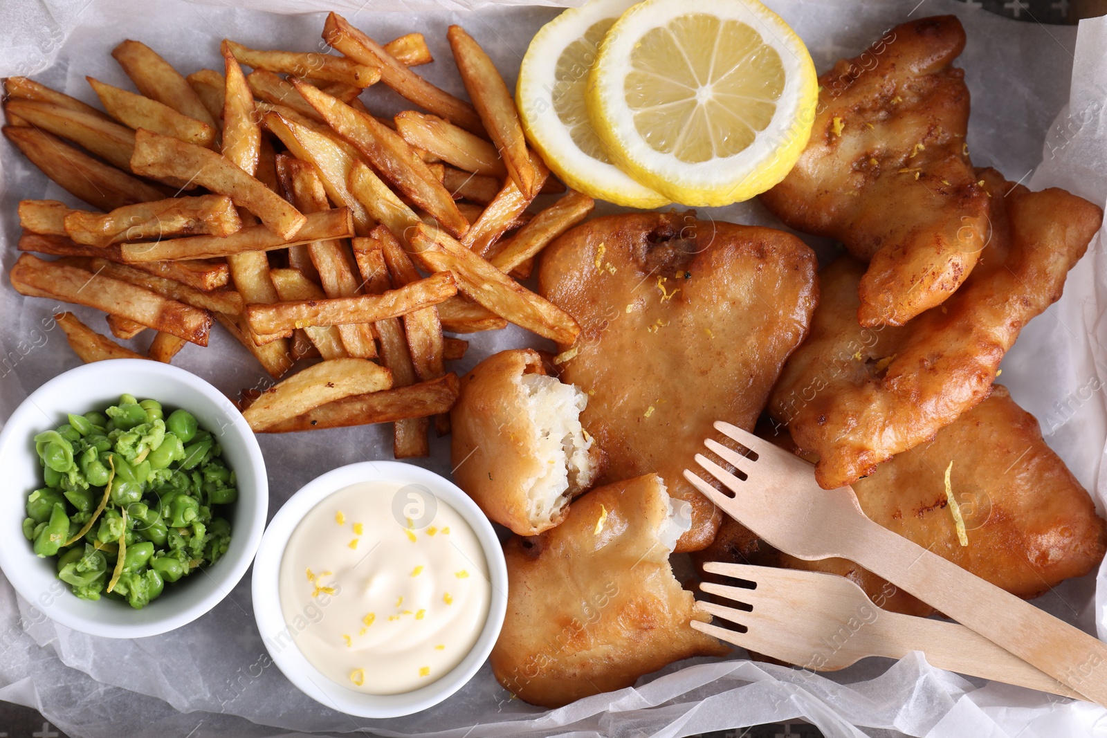 Photo of Tasty fish, chips, sauce and peas on tray, top view