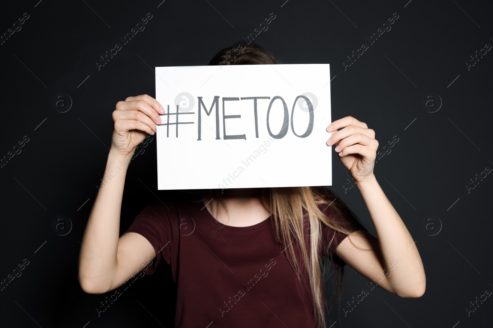 Photo of Young woman holding #METOO card against dark background