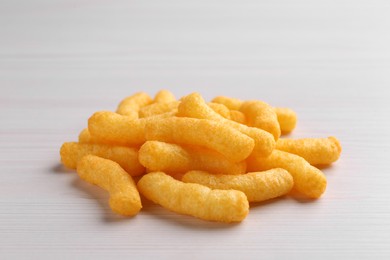 Heap of tasty cheesy corn puffs on white wooden table