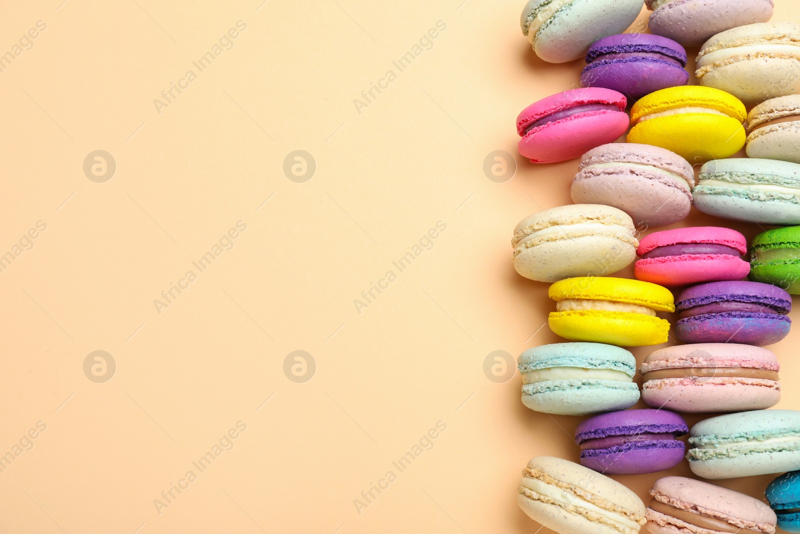 Photo of Delicious colorful macarons on beige background, flat lay. Space for text