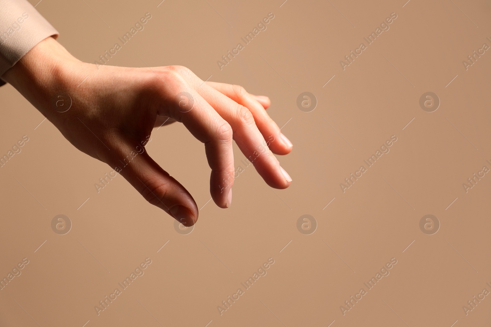 Photo of Woman holding something in hand on beige background, closeup. Space for text