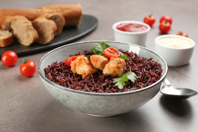 Photo of Tasty brown rice with chicken on grey table