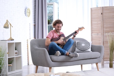 Young man playing electric guitar in living room