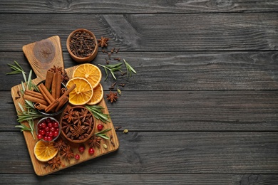 Photo of Flat lay composition with mulled wine ingredients on black wooden table. Space for text