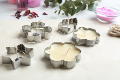 Photo of Handmade candles with cutters and paper on table