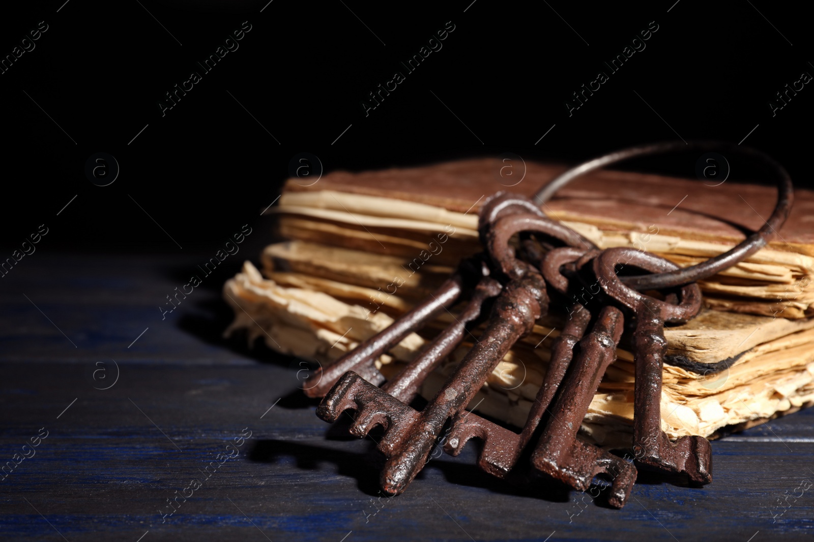 Photo of Bunch of old vintage keys with books on wooden table, space for text