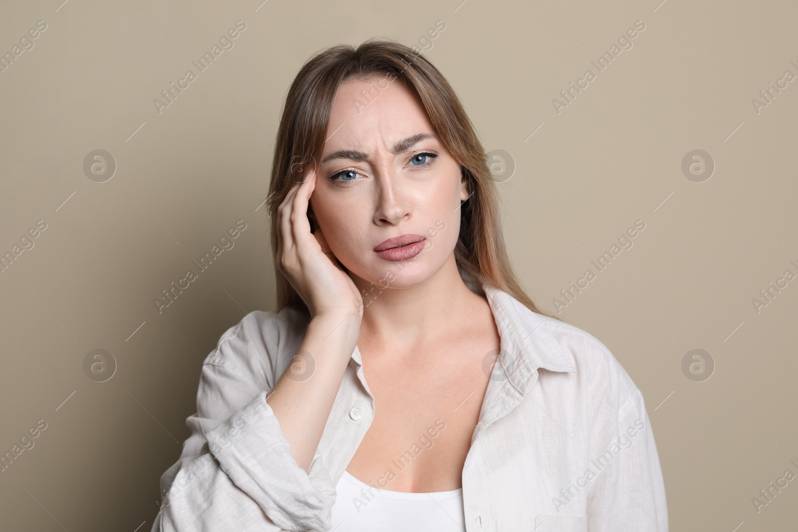 Photo of Young woman suffering from headache on beige background