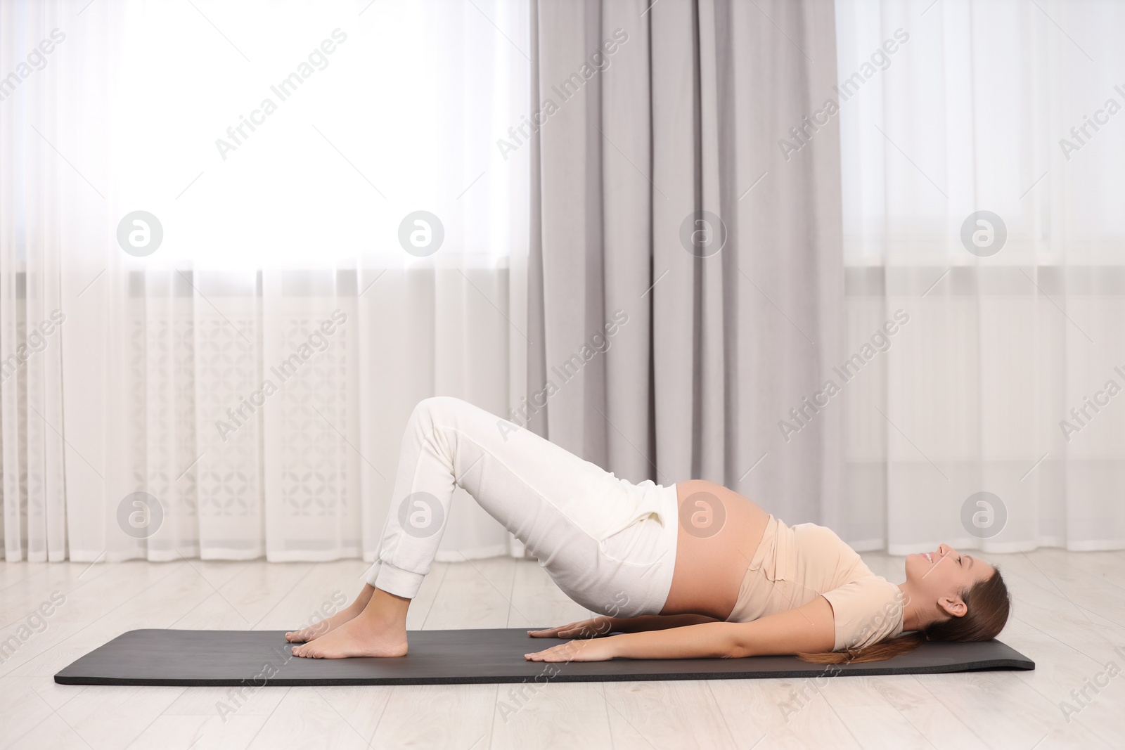 Photo of Pregnant woman doing exercises on yoga mat at home