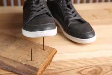 Nails in wooden plank and shoes on table