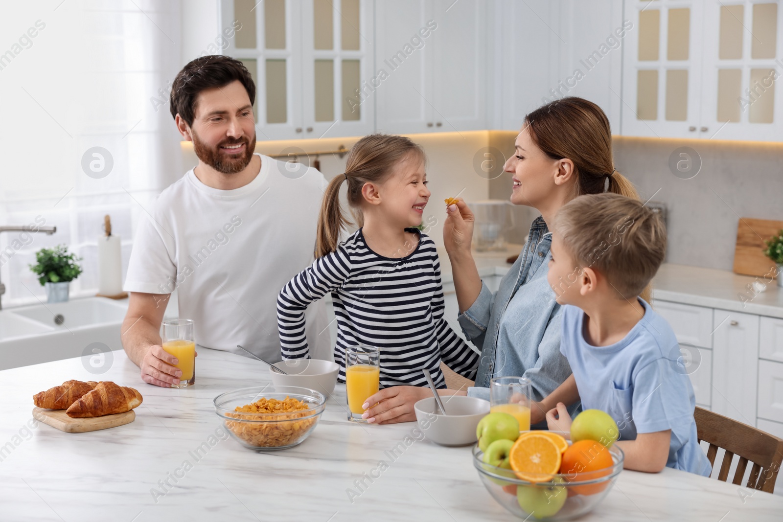 Photo of Happy family having breakfast at table in kitchen