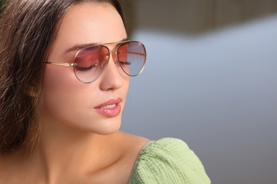 Photo of Beautiful woman in sunglasses outdoors, space for text