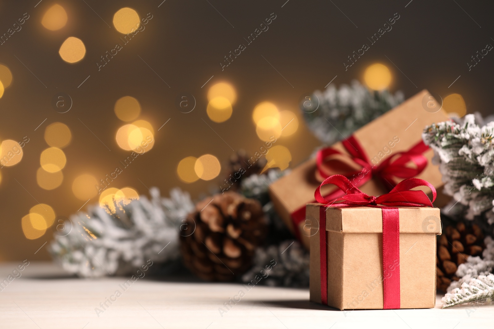 Photo of Gift boxes and Christmas decor on wooden table against blurred festive lights, space for text