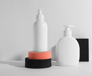 Photo of Bottles with different cosmetic products and podiums on white background