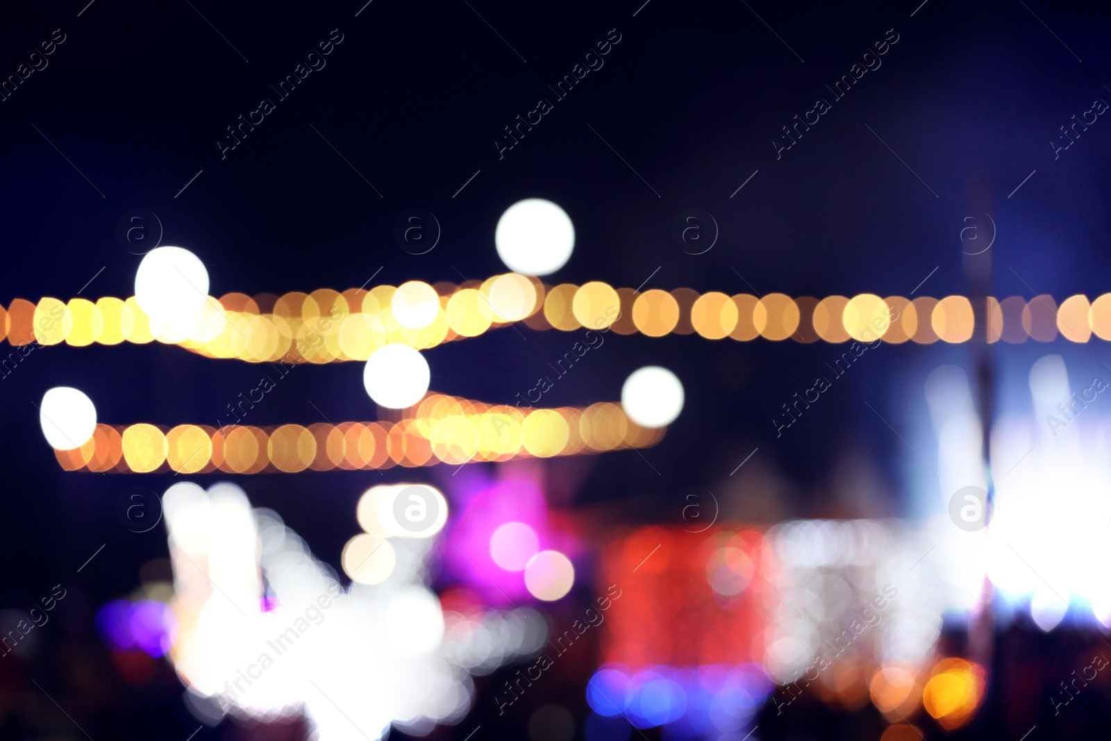 Photo of Blurred view of city street with festive lights at night. Bokeh effect