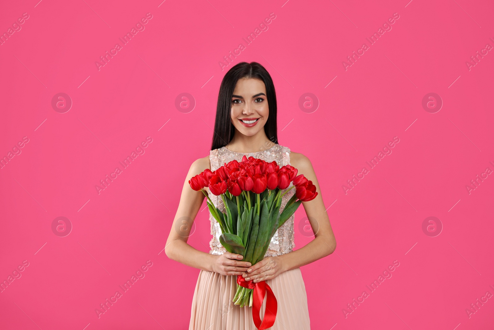 Photo of Happy woman with red tulip bouquet on pink background. 8th of March celebration