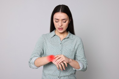 Image of Arthritis symptoms. Young woman suffering from pain in wrist on light grey background