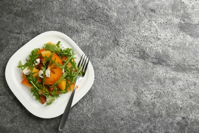 Delicious persimmon salad served on grey table, top view. Space for text