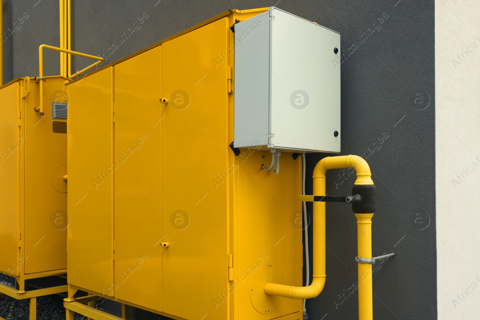 Photo of Yellow gas distribution cabinet near brown wall outdoors