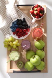 Photo of Glasses of different tasty smoothies and fresh ingredients on white wooden table, top view