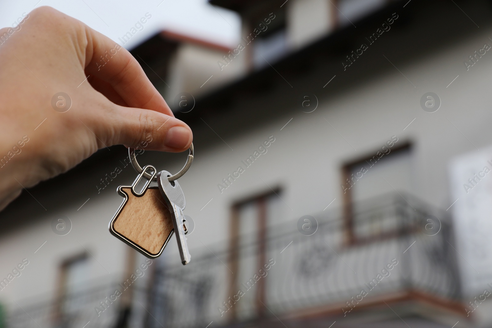 Photo of Woman holding house keys outdoors, closeup with space for text. Real estate agent