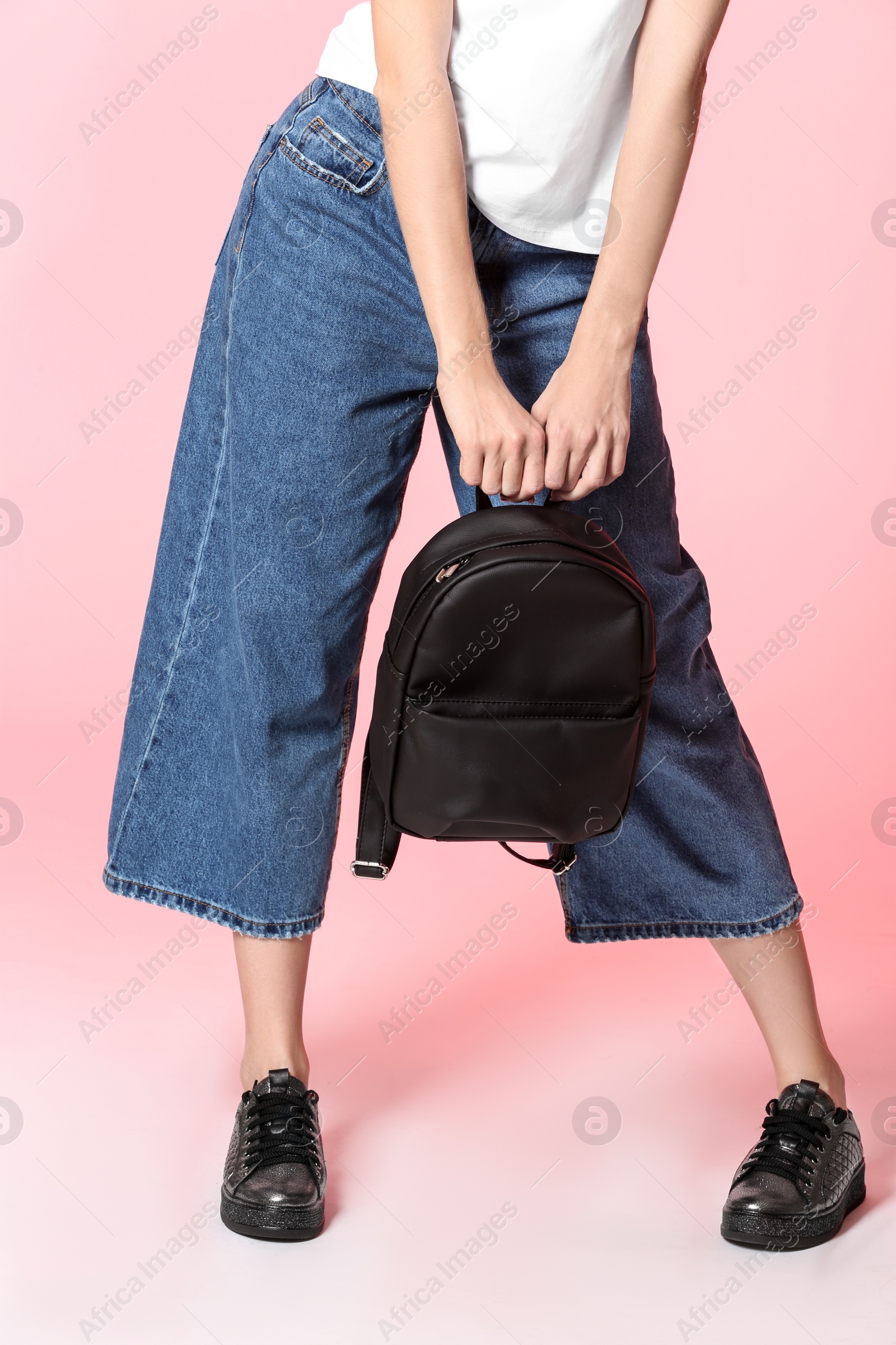 Photo of Fashionable woman in stylish shoes with backpack on color background