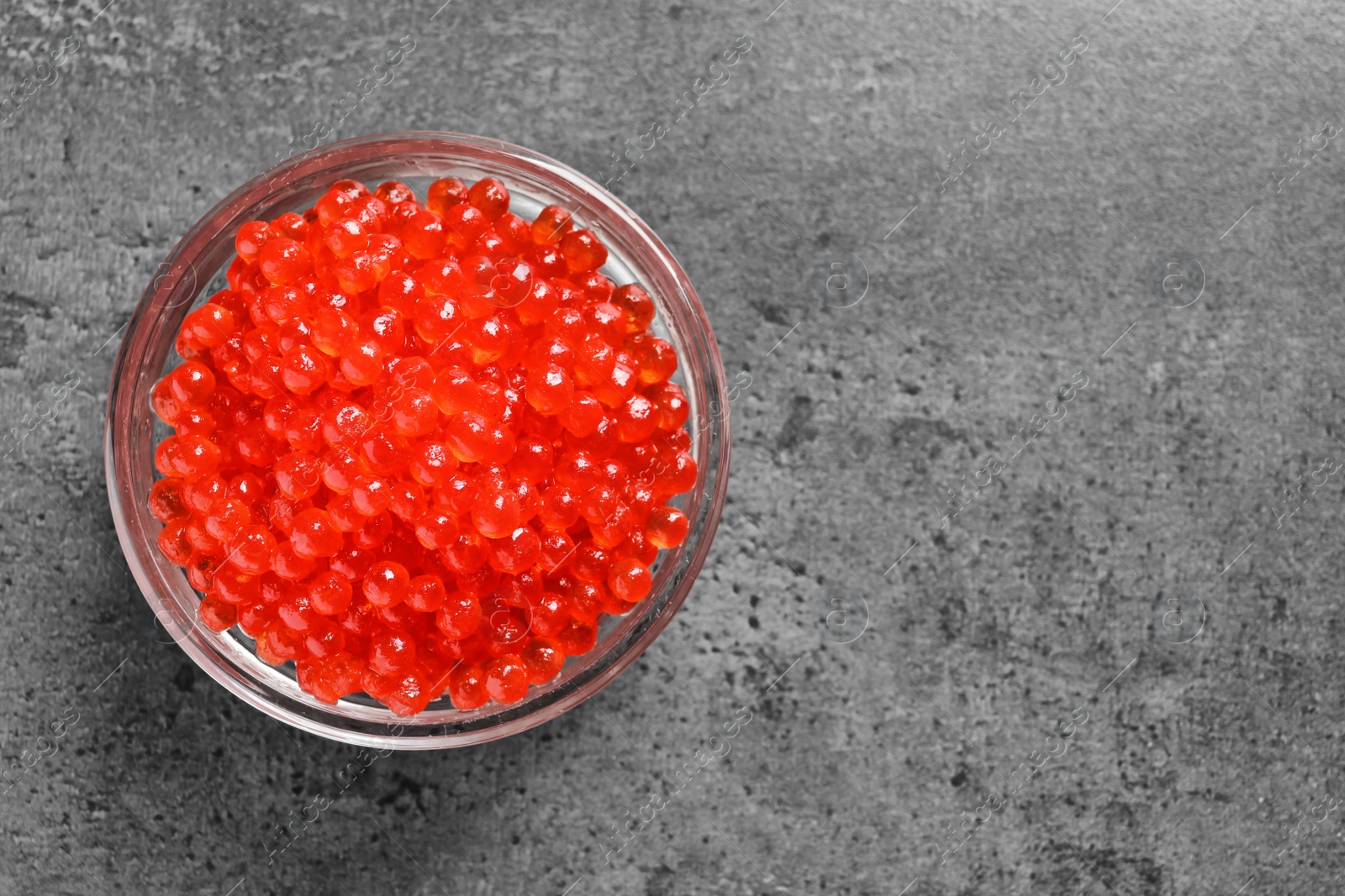 Photo of Glass bowl with delicious red caviar on table