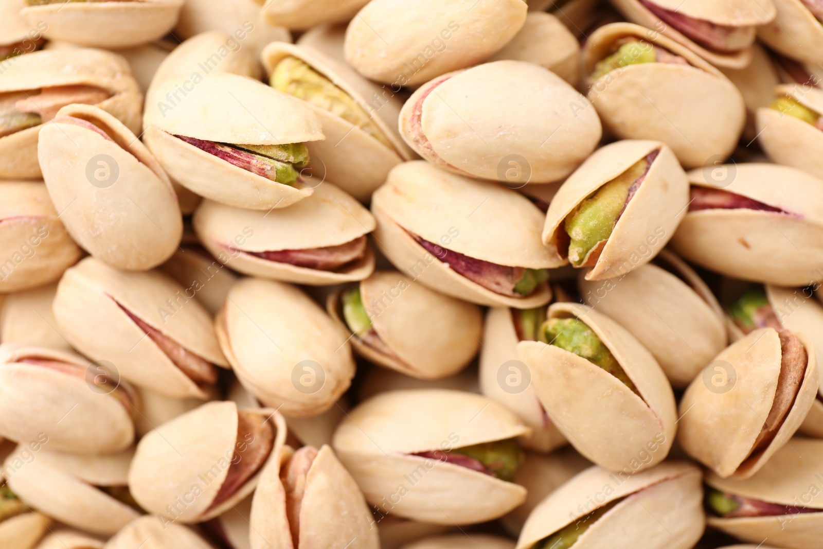 Photo of Tasty unpeeled pistachios as background, top view