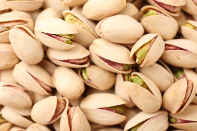 Photo of Tasty unpeeled pistachios as background, top view