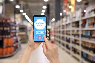 Image of Woman holding smartphone with activated promo code in supermarket, closeup