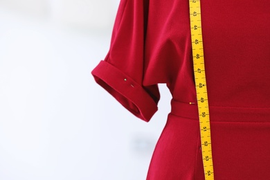 Photo of Mannequin with dress and measuring tape in tailor studio, closeup