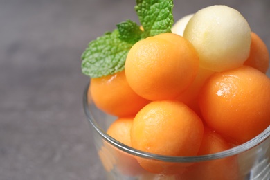 Melon balls and mint in glass on grey table, closeup. Space for text