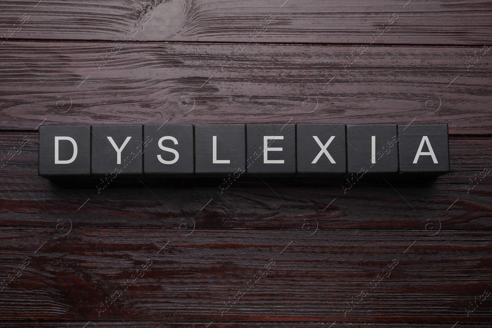 Photo of Black cubes with word Dyslexia on wooden background, flat lay