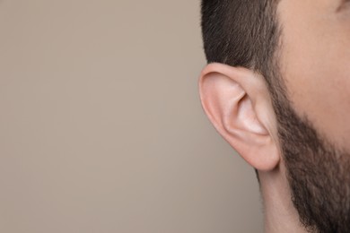 Photo of Man on grey background, closeup of ear. Space for text