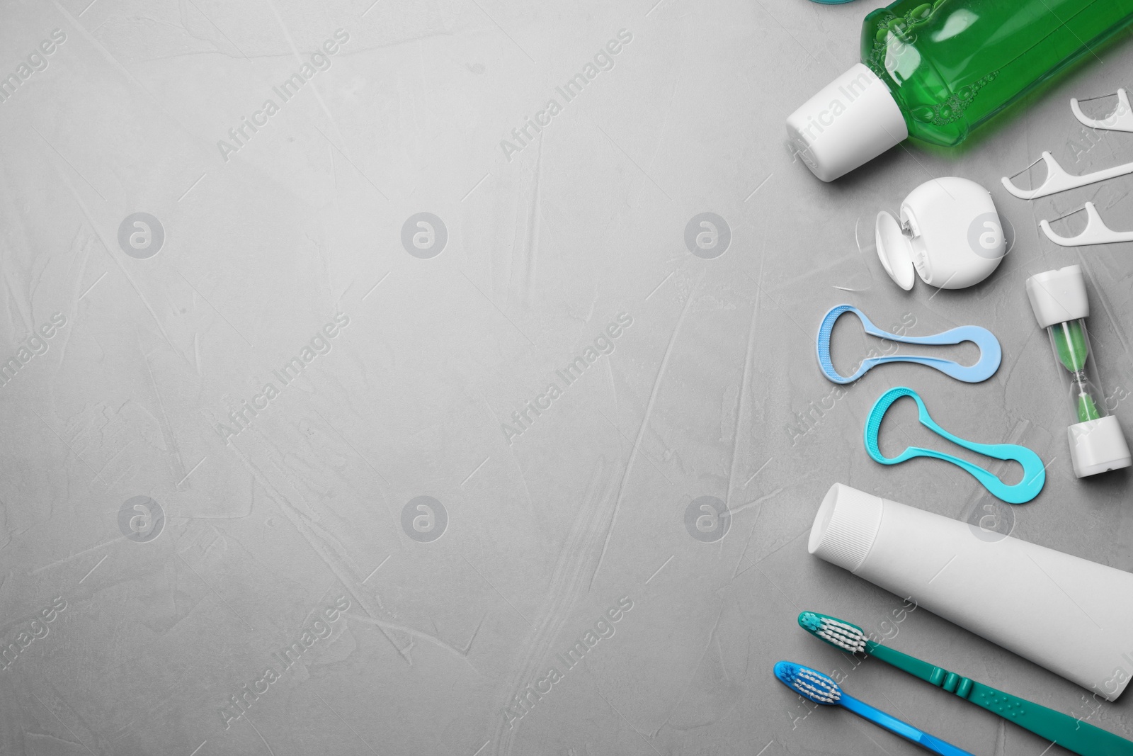 Photo of Flat lay composition with tongue cleaners and teeth care products on grey background. Space for text