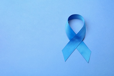 Photo of Blue ribbon on color background, top view with space for text. Colon cancer awareness concept