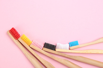 Toothbrushes made of bamboo on pink background, flat lay. Space for text