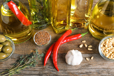 Photo of Different cooking oils in bottles on wooden table