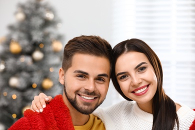 Photo of Happy young couple near Christmas tree at home