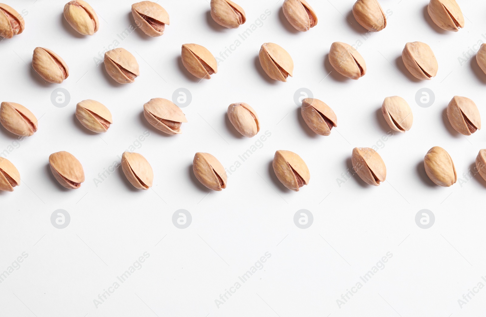 Photo of Organic pistachio nuts on white background, flat lay. Space for text