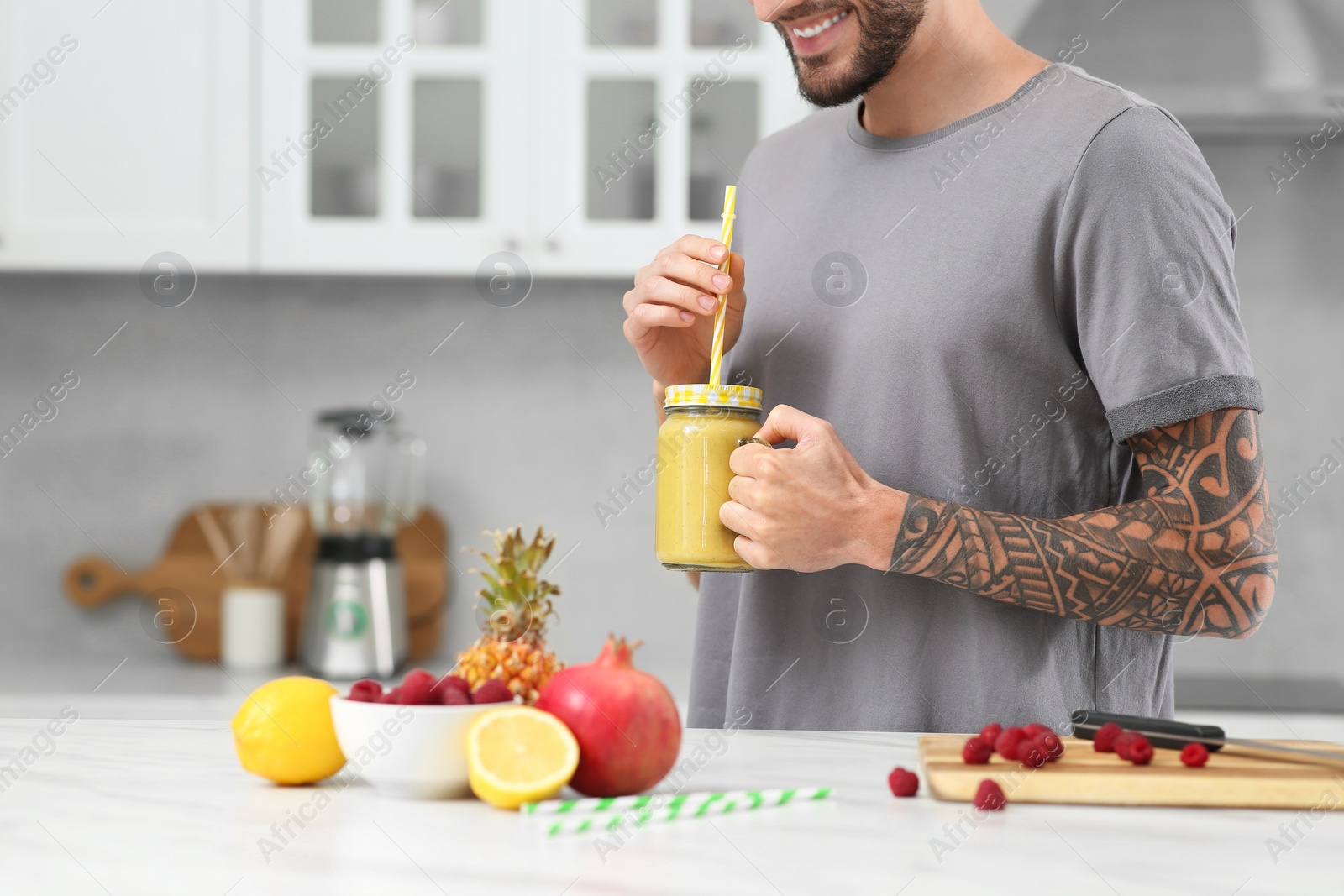 Photo of Man with delicious smoothie in kitchen, closeup. Space for text