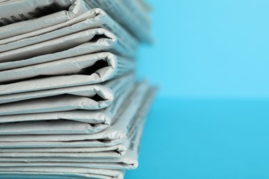 Photo of Stack of newspapers on light blue background, closeup with space for text. Journalist's work