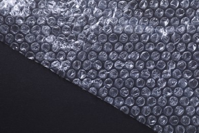 Photo of Transparent bubble wrap on black background, top view. Space for text