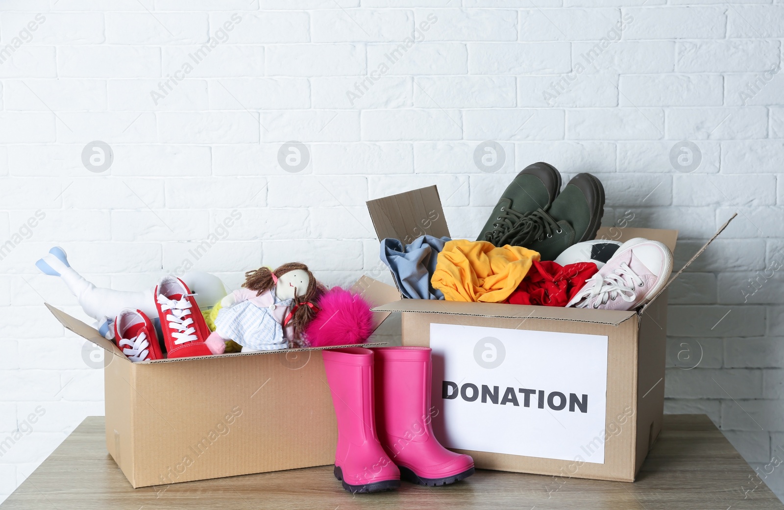 Photo of Carton boxes with donations on table near brick wall