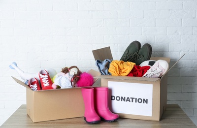 Carton boxes with donations on table near brick wall