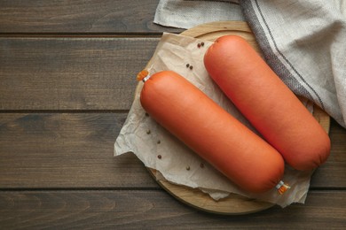 Photo of Board with tasty boiled sausages on wooden table, top view. Space for text