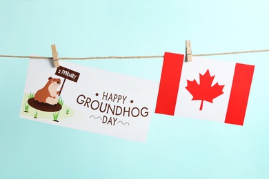 Photo of Happy Groundhog Day greeting card and Canada flag hanging on turquoise background